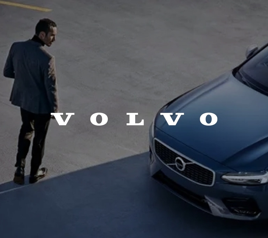 A man in a business suit gazing at a Volvo car, with a white Volvo logo overlay.